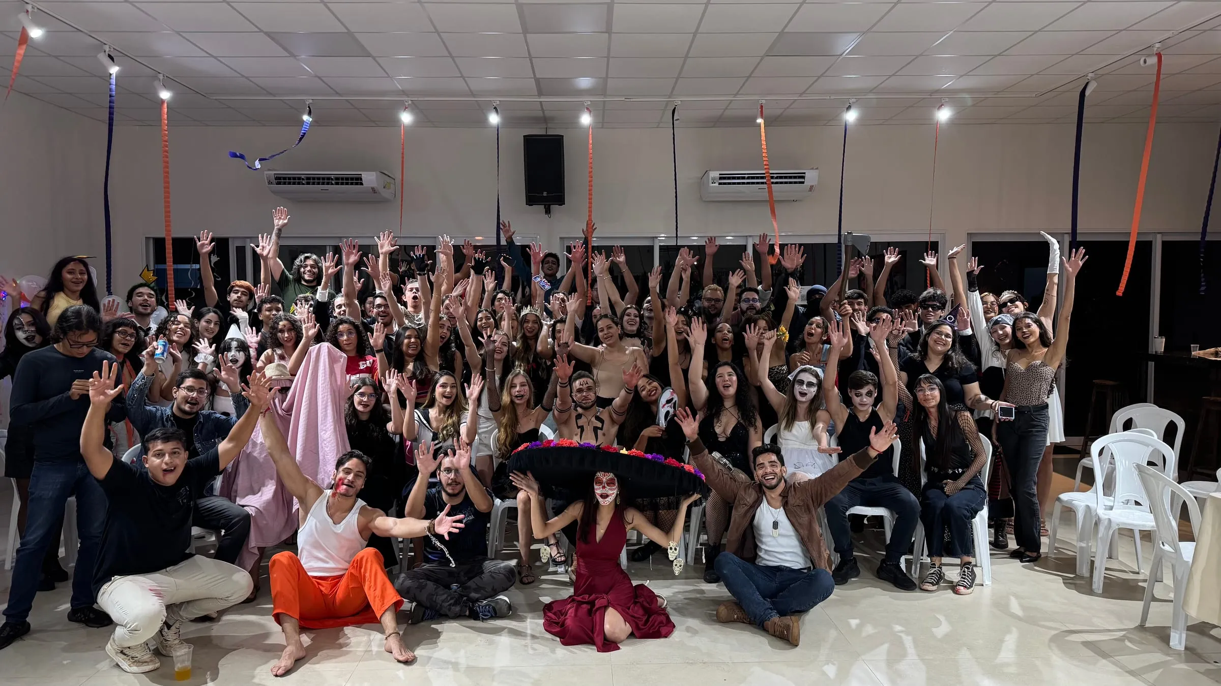 Participantes fantasiados comemorando no salão do SpookUp, a edição de Halloween